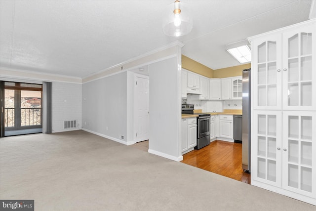 kitchen with white cabinets, light colored carpet, ornamental molding, and appliances with stainless steel finishes