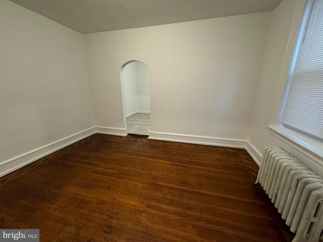 spare room featuring dark hardwood / wood-style flooring and radiator