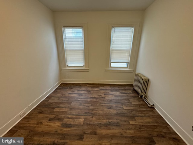 spare room featuring dark hardwood / wood-style flooring and radiator heating unit