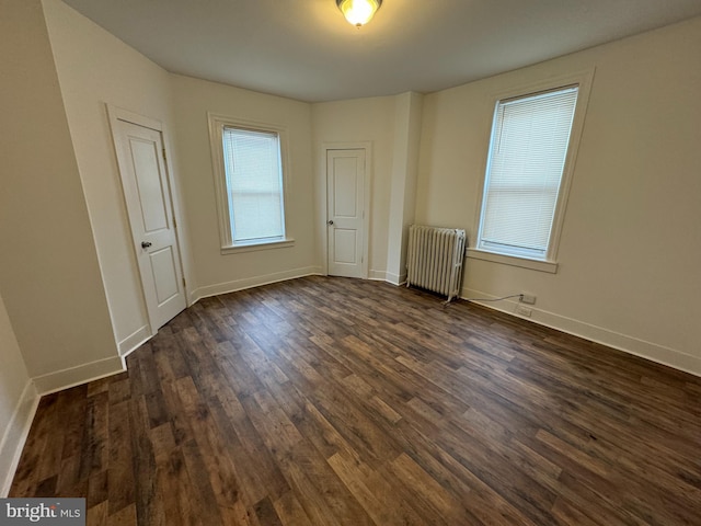 spare room with dark hardwood / wood-style flooring and radiator heating unit