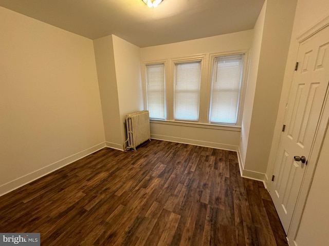 empty room featuring dark hardwood / wood-style flooring and radiator heating unit