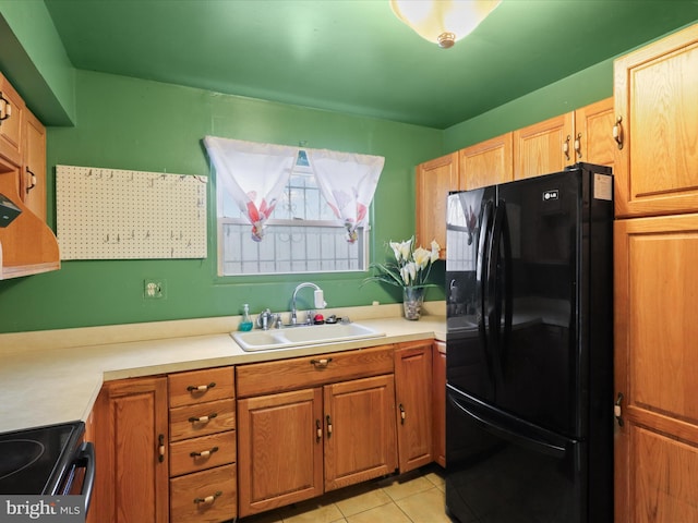 kitchen featuring range, black refrigerator, light tile patterned floors, and sink