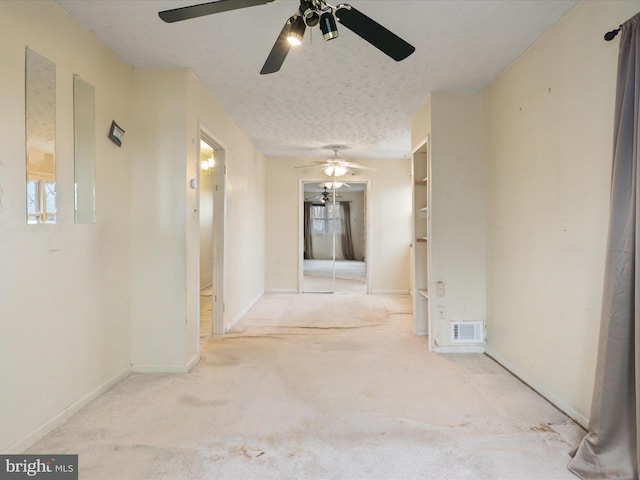 hall featuring light colored carpet and a textured ceiling