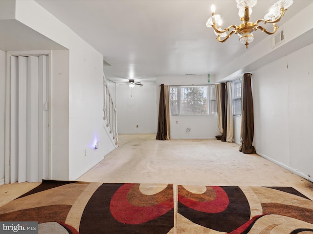 unfurnished room with ceiling fan with notable chandelier and light colored carpet