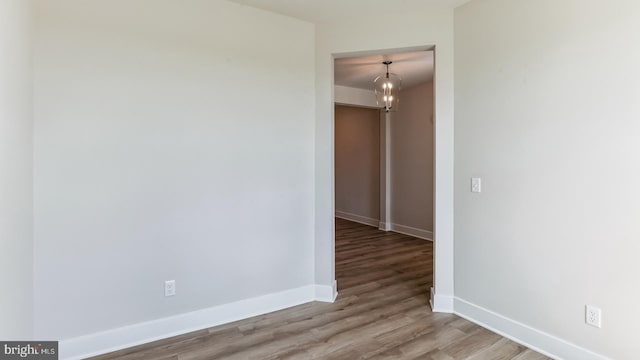 spare room with light hardwood / wood-style floors and a notable chandelier