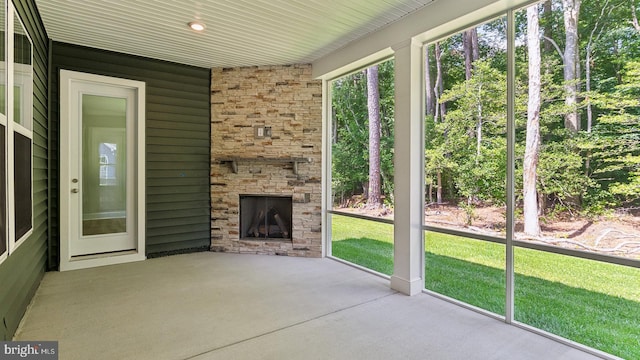 unfurnished sunroom with an outdoor stone fireplace