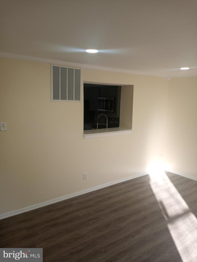 empty room featuring dark hardwood / wood-style flooring and ornamental molding