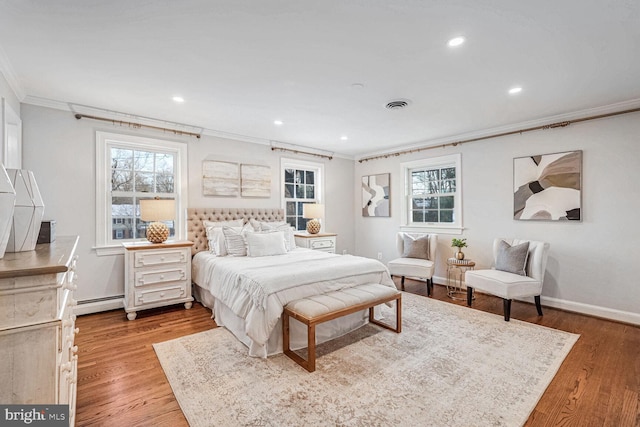 bedroom with light hardwood / wood-style floors, ornamental molding, and baseboard heating