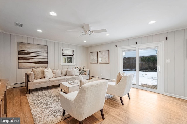 living room with a baseboard radiator, light hardwood / wood-style flooring, ceiling fan, and crown molding