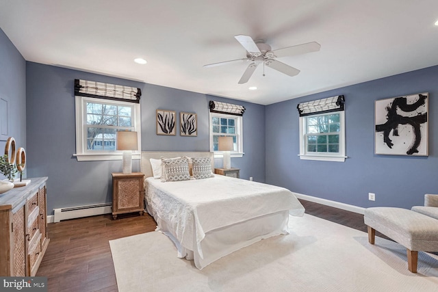 bedroom with dark hardwood / wood-style flooring, baseboard heating, and ceiling fan