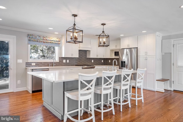 kitchen with white cabinetry, sink, decorative light fixtures, a kitchen island, and appliances with stainless steel finishes