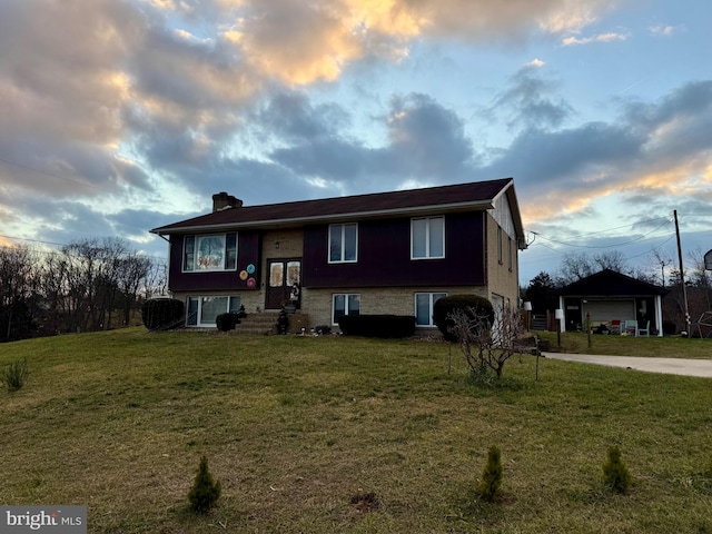 split foyer home featuring a lawn, a garage, and an outbuilding