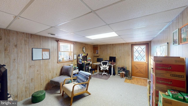 carpeted home office with a paneled ceiling, wooden walls, and a wealth of natural light