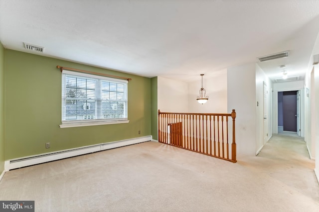 spare room with light carpet and a baseboard heating unit