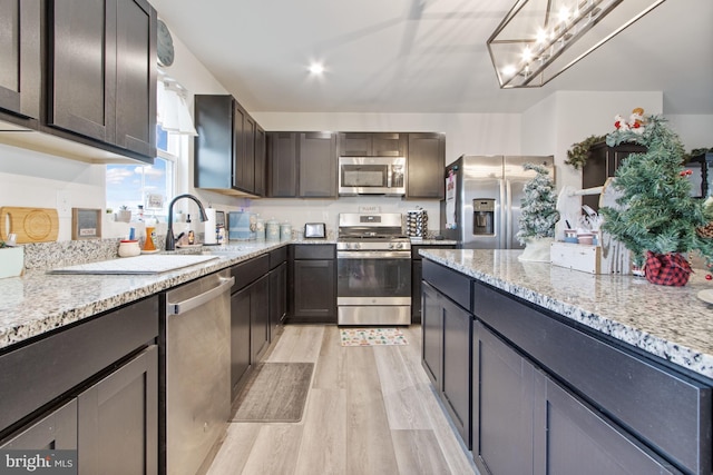 kitchen with light stone countertops, appliances with stainless steel finishes, light hardwood / wood-style flooring, and dark brown cabinets