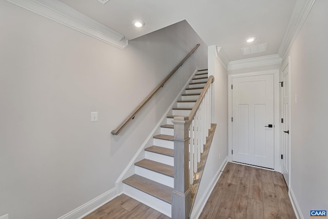 staircase featuring ornamental molding and hardwood / wood-style flooring