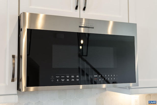 details with decorative backsplash and white cabinetry