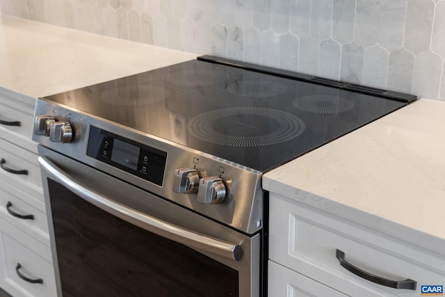 room details with white cabinets and stainless steel stove