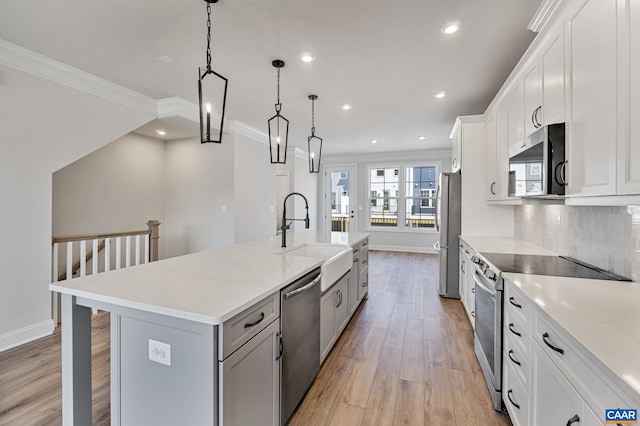 kitchen with stainless steel appliances, sink, light hardwood / wood-style flooring, white cabinetry, and a large island