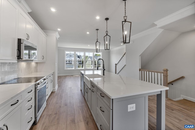 kitchen featuring a spacious island, white cabinetry, appliances with stainless steel finishes, and light hardwood / wood-style flooring