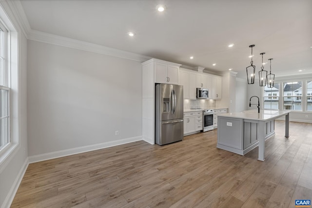 kitchen with a kitchen island with sink, white cabinets, light hardwood / wood-style flooring, appliances with stainless steel finishes, and decorative light fixtures