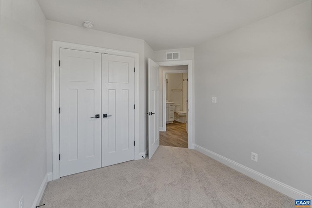 unfurnished bedroom featuring light carpet and a closet