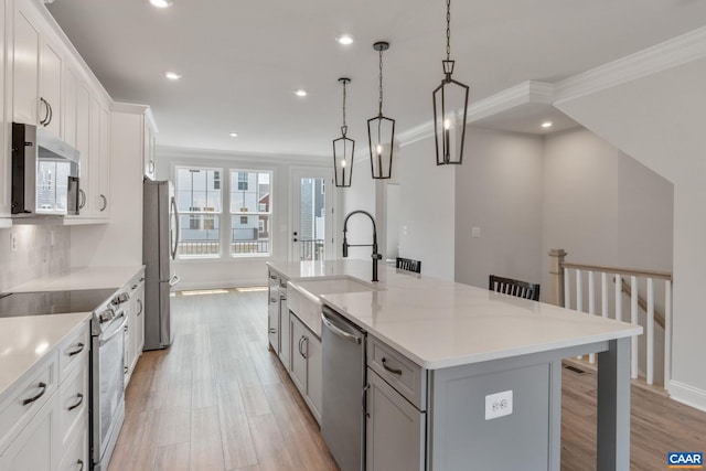 kitchen with a kitchen bar, a large island with sink, white cabinets, and appliances with stainless steel finishes