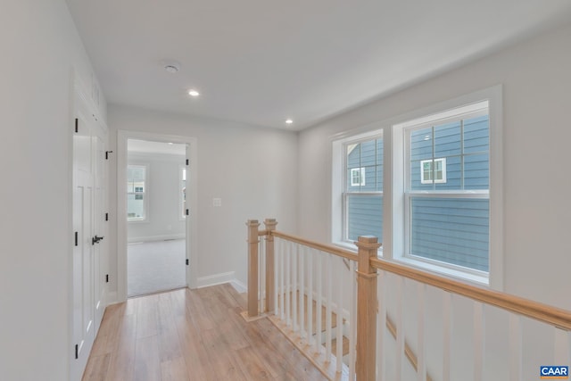 hall with a wealth of natural light and light hardwood / wood-style flooring