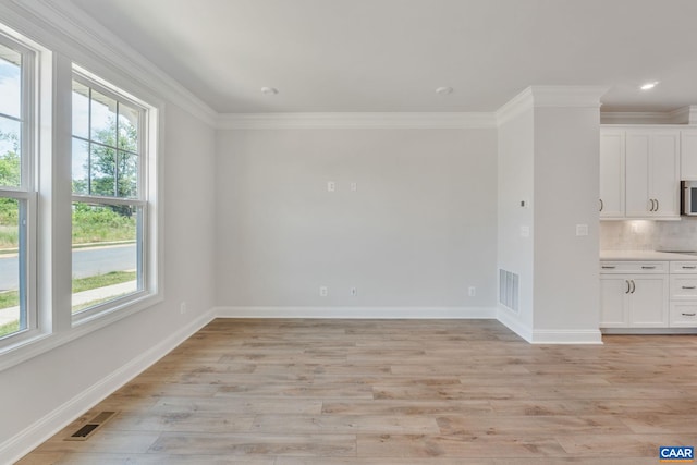 interior space with a wealth of natural light, light hardwood / wood-style flooring, and crown molding