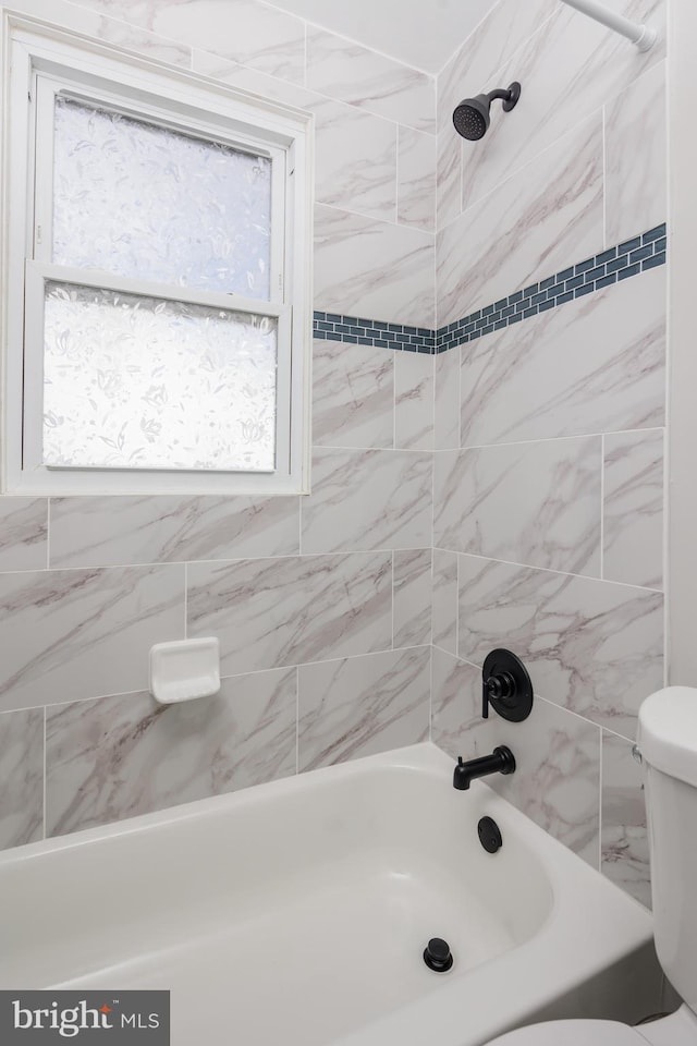 bathroom with tiled shower / bath combo and toilet