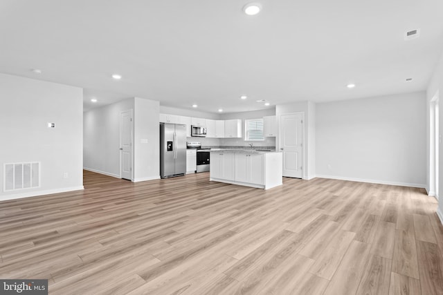 unfurnished living room with light hardwood / wood-style flooring and sink