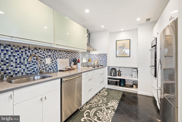 kitchen with sink, tasteful backsplash, dark tile patterned floors, white cabinets, and appliances with stainless steel finishes