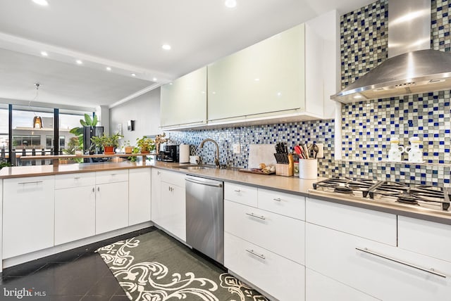 kitchen with white cabinets, wall chimney range hood, sink, decorative backsplash, and stainless steel appliances