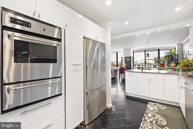 kitchen featuring white cabinets, kitchen peninsula, and stainless steel appliances