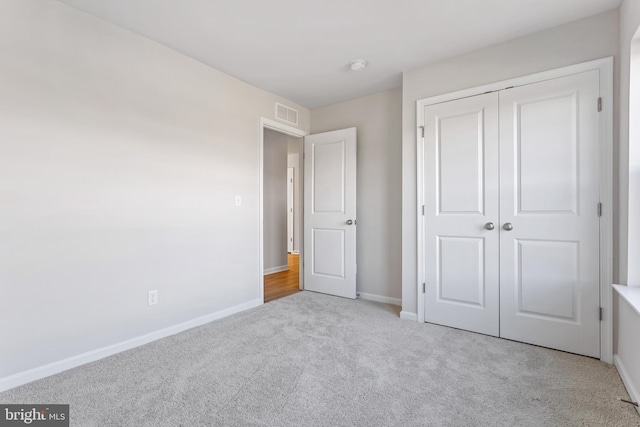 unfurnished bedroom with light carpet and a closet