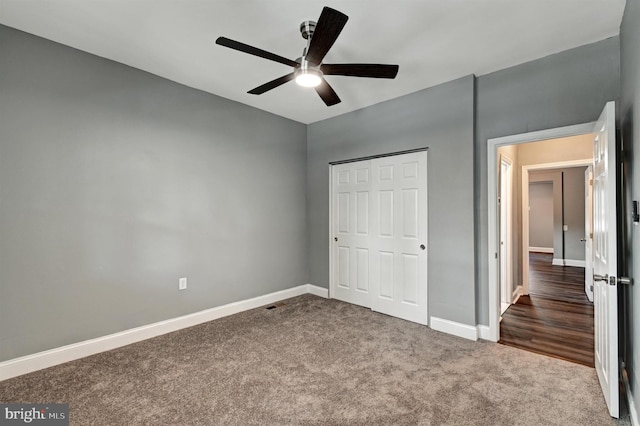 unfurnished bedroom with ceiling fan, a closet, and dark carpet