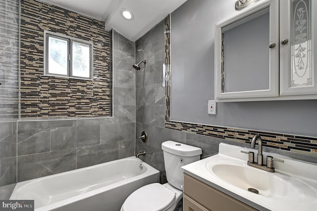 full bathroom featuring vanity, toilet, tile walls, and tiled shower / bath