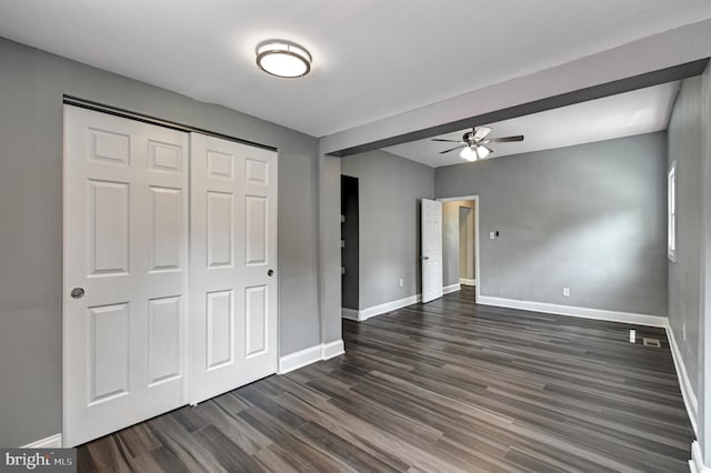 unfurnished bedroom featuring a closet, dark wood-type flooring, and ceiling fan