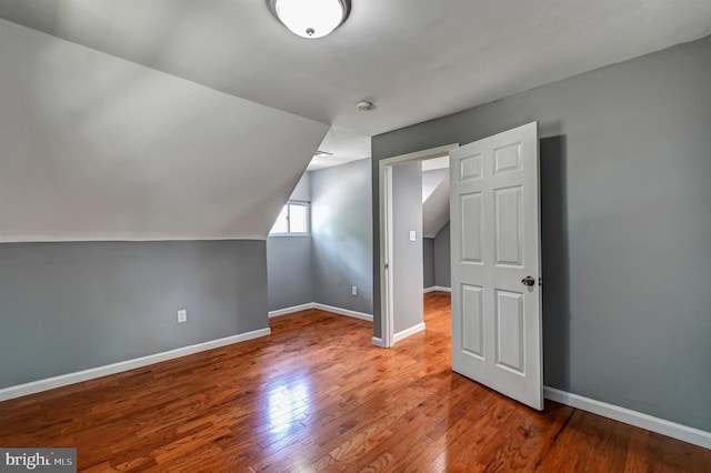 bonus room with hardwood / wood-style flooring and vaulted ceiling