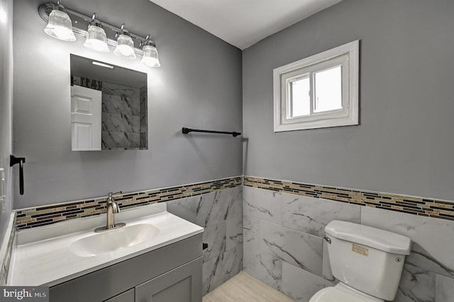 bathroom featuring vanity, a shower, toilet, and tile walls