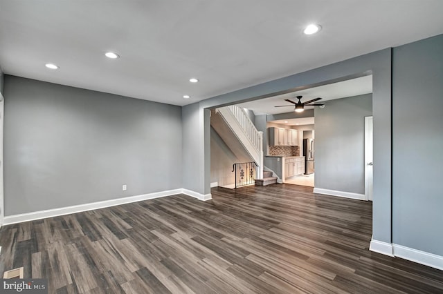 unfurnished living room featuring ceiling fan and dark wood-type flooring