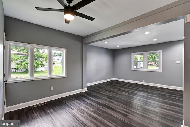 unfurnished room with a wealth of natural light, dark wood-type flooring, and ceiling fan