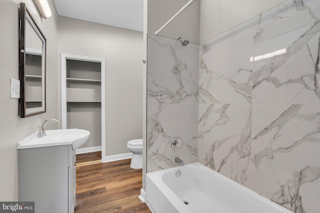 full bathroom featuring hardwood / wood-style floors, tiled shower / bath combo, toilet, and vanity