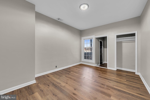 unfurnished bedroom with dark hardwood / wood-style flooring and a closet