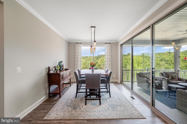 dining area featuring dark wood-type flooring, ceiling fan with notable chandelier, and ornamental molding