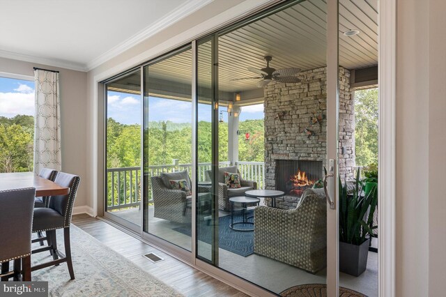 doorway to outside with ceiling fan, a fireplace, crown molding, and hardwood / wood-style flooring