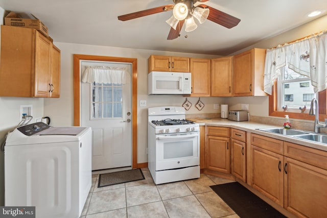 kitchen featuring white appliances, a wealth of natural light, separate washer and dryer, light tile patterned flooring, and sink