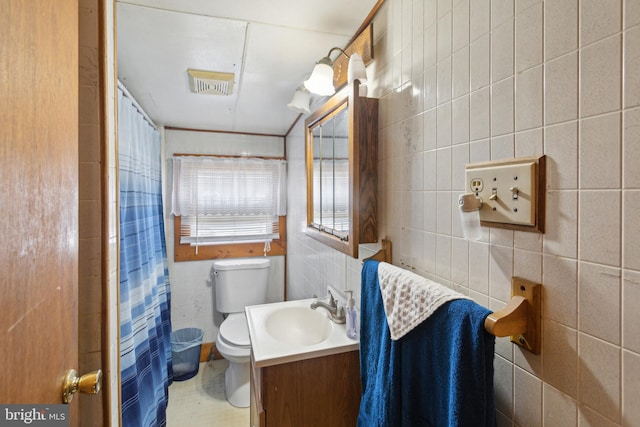 bathroom with tile walls, a shower with curtain, vanity, and toilet