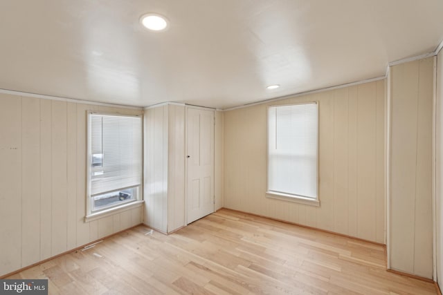 unfurnished bedroom featuring wooden walls and light wood-type flooring