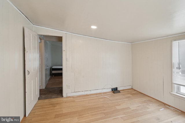 spare room featuring light hardwood / wood-style flooring, wooden walls, and lofted ceiling